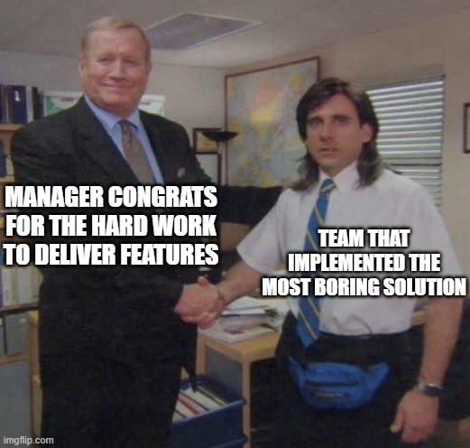 The office congratulation meme. Featuring two men shaking hands in a business setting. One looks like a manager, the other like out of place with a tie but also with a mullet and a bum bag. Caption: Manager congrat for the hard work to deliver features - Team that implemented the most boring solution.